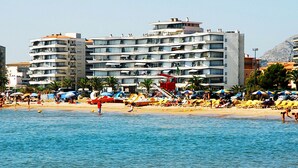 Ein Strandhotel mit mehreren Balkonen, einem Poolbereich und Sonnenschirmen.