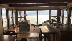 Un amplio salón con vistas al mar, una mesa de comedor y una zona de cocina.