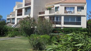 A multi-story building with balconies, large windows, and a tiled roof. - SEAFRONT APARTMENT WITH SWIMMING POOL (Saint-Cyprien)