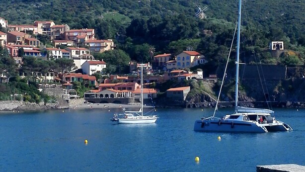 A coastal town with a historic castle on a hill, boats on the water, and people relaxing on the beach. - SEAFRONT APARTMENT WITH SWIMMING POOL (Saint-Cyprien)