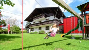 A child on a swing in a grassy yard with a building in the background. - Ferienwohnung 35m² (Kötschach-Mauthen)