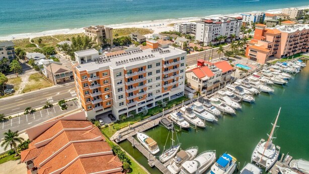 Ein Küstenhotel mit mehreren Gebäuden, einer Marina mit Booten und einem Strand im Hintergrund.