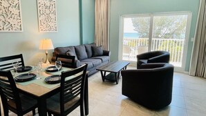 Ein Wohnzimmer mit Essbereich, einer Couch, einem Couchtisch und einem Sessel.
