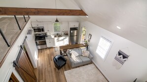 A compact kitchen with modern appliances, a dining area with a sofa, and a staircase leading to an upper level. - The Aspen . Trailside Lodging (Millersburg)