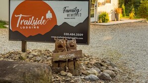 A sign for Trailside Lodging with a 'Family Memories Made Here' message, a welcome sign, and a contact number. - The Aspen . Trailside Lodging (Millersburg)