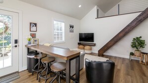 A modern kitchen with a wooden bar, bar stools, a television, and a staircase. - The Aspen . Trailside Lodging (Millersburg)