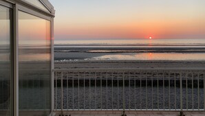 Ein Balkon mit Blick auf den Sonnenuntergang über dem Strand.