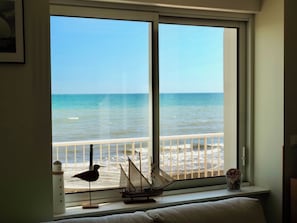 A room with a large window overlooking a beach. - Maison Spacieuse Front de mer (Quinéville)