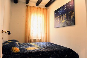 A bedroom with a bed, a window with curtains, and a painting on the wall. - Spacious two-bedroom, two-bathroom apartment in old town, Biennale area (Venezia)