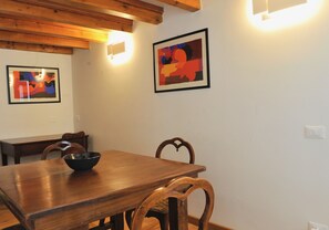 A wooden dining table with a black bowl, wooden chairs, and two framed abstract paintings on the wall. - Spacious two-bedroom, two-bathroom apartment in old town, Biennale area (Venezia)