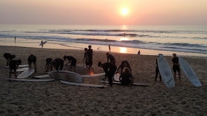A beach scene with people and surfboards at sunset.