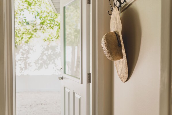 A straw hat hanging on a wall near a door with a view of greenery outside. - Ideal Location, Stunning Villa! Close to beach, beach gear provided! (Anna Maria)