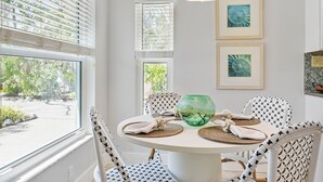 A dining area with a round table, four patterned chairs, a green fish bowl, and framed artwork on the wall. - Ideal Location, Stunning Villa! Close to beach, beach gear provided! (Anna Maria)