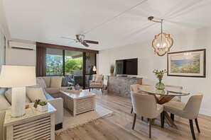 A modern living room with a sofa, coffee table, and dining area. - Updated Kamaole Sands Condo (Kihei)