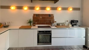 A modern kitchen with white cabinetry, a brick backsplash, and a built-in oven. - House with garden downtown (Sète)