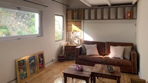 A cozy living room with a brown leather sofa, wooden coffee table, and framed pictures on the wall. - House with garden downtown (Sète)