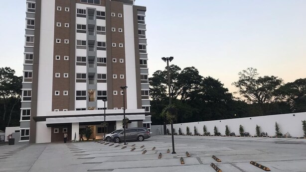 A multi-story hotel with a modern design, featuring a parking area in front. - Exclusive Apartment Arboleda 186 (San Pedro Sula)