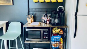 A kitchen with a microwave, coffee maker, and a fruit basket.