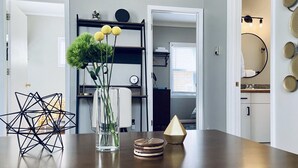 A dining table with a geometric sculpture, a vase with green plants, and a pyramid-shaped object.