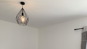 Un salon moderne avec un canapé marron, une table basse blanche et une suspension au design géométrique.