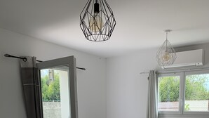Un salon moderne comprenant un canapé, une table à manger, des chaises et un luminaire suspendu.