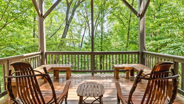 Eine Holzterrasse mit einem Pavillon, umgeben von üppigen, grünen Bäumen.