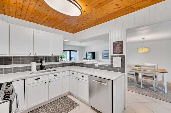 A modern kitchen with white cabinetry, a black faucet, and a patterned backsplash. - Waterfront/Pool mins to Siesta Key Beach-bikes/kayaks/SUPS incd- paddle to beach (Sarasota)