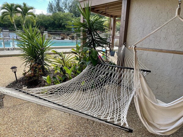A hammock set up on a gravel patio with a pool and palm trees in the background. - Waterfront/Pool mins to Siesta Key Beach-bikes/kayaks/SUPS incd- paddle to beach (Sarasota)