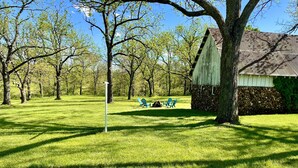 A grassy area with a wooden structure, two blue chairs, and a flagpole. - Countryside paradise 6 miles to Stockton Lake! We now have high-speed internet! (Stockton)