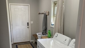 A laundry room with a washing machine, dryer, and a small table with a basket and a towel rack. - Countryside paradise 6 miles to Stockton Lake! We now have high-speed internet! (Stockton)
