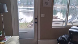 A living room with a door leading to a lake view, a couch, a lamp, a rug, and a sign on the wall. - Bluegill lake -Lake front retreat (Harrison)