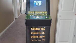 A Golden Tee arcade machine in a hallway with beige walls and a carpeted floor. - Bluegill lake -Lake front retreat (Harrison)