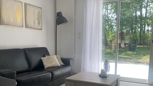 Una sala de estar moderna con un sofá de cuero negro, una mesa de centro de madera y un ventanal con vista a un jardín.