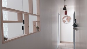 Un pasillo estrecho con un diseño geométrico en la ventana, un globo decorativo en la pared y piso de baldosas.
