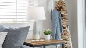 A modern living room with a grey sofa, a wooden coffee table, a lamp, and a plant. - Beachfront 3BR Condo with Oversized Gulf View Balcony, Pool and Spa (Indian Shores)