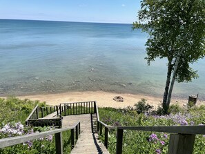 A wooden staircase leading to a beach with clear water and a tree on the right. - Amazing lake view and peaceful cottage with kayaks (Forestville)