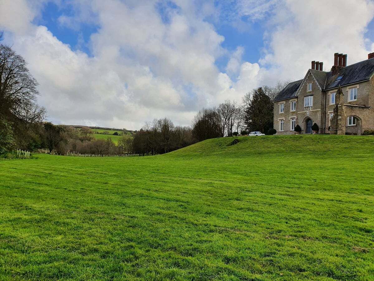 A large grassy field with a stone building in the background.