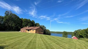 Une maison avec une grande pelouse et un lac en arrière-plan.