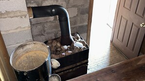 Un intérieur rustique avec un poêle à bois, un seau en métal et une porte.