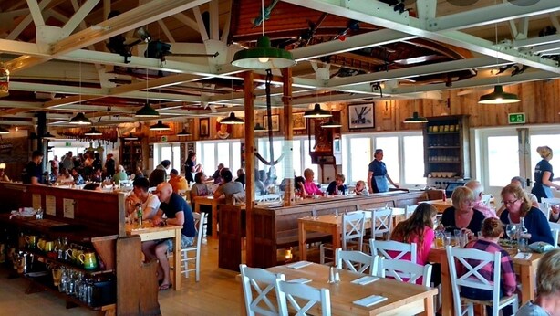 A busy restaurant with wooden interiors, multiple dining tables, and a bar area. - Property 5 Minutes Walk From Trearddur Bay Beach (Holyhead)