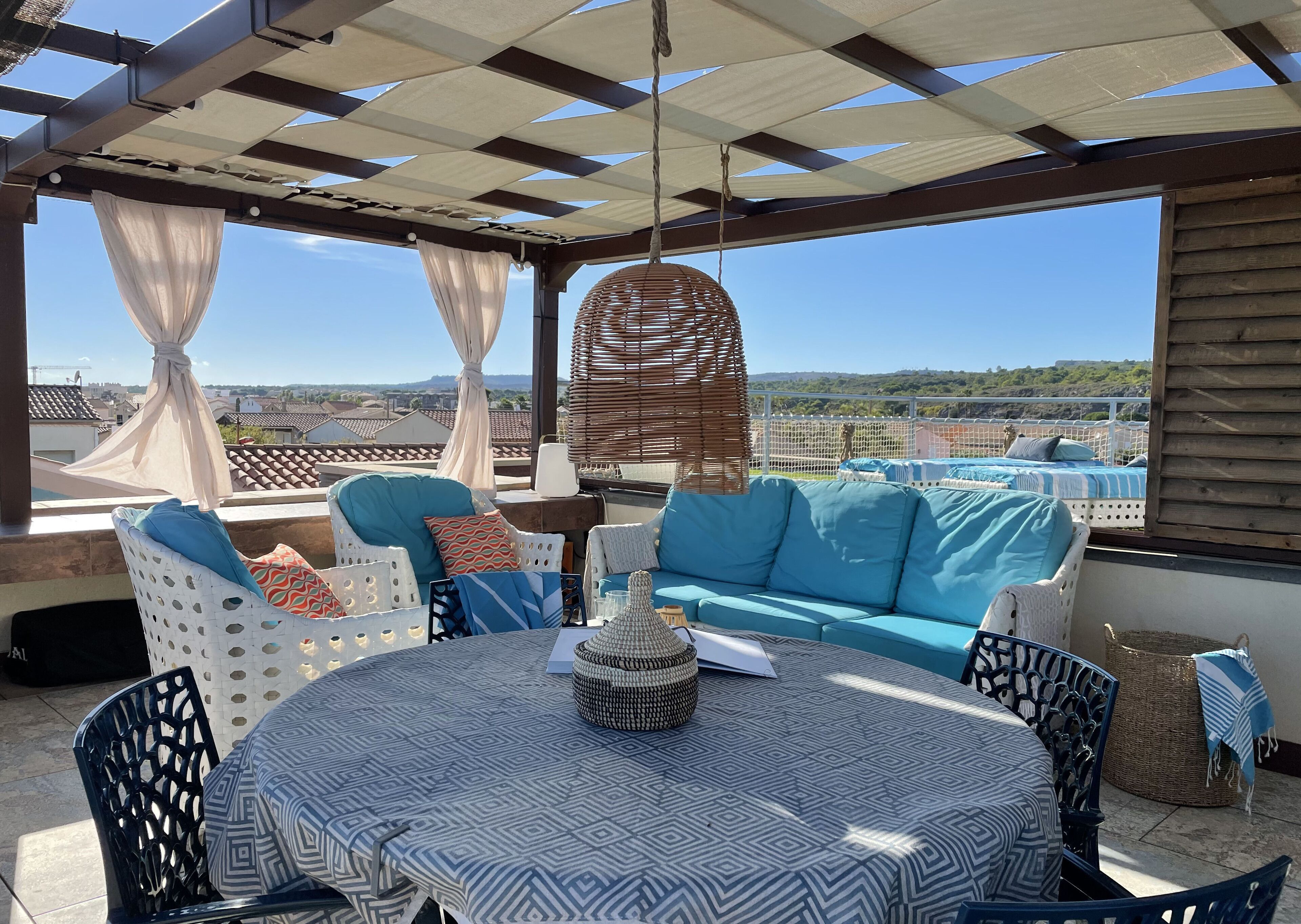 Un espace extérieur abrité, aménagé avec une table, des chaises et un canapé.