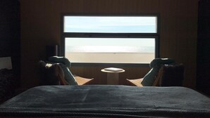 A room with a large window overlooking a beach, a bed, two chairs, and a small table. - Seafront -  feet in the sand - the most beautiful view of Narbonne Plage (Narbonne Plage)