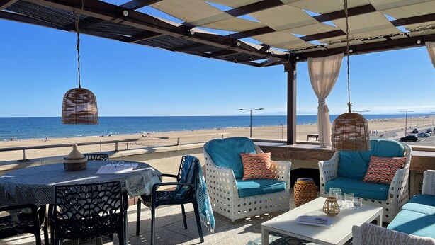 An outdoor seating area with wicker chairs and tables, overlooking a beach. - Seafront -  feet in the sand - the most beautiful view of Narbonne Plage (Narbonne Plage)