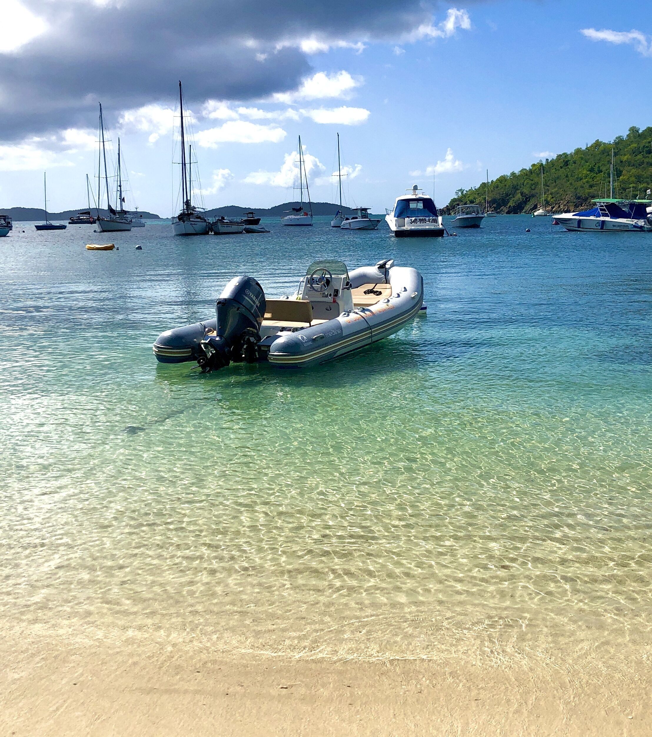 A clear beach with a small inflatable boat anchored near the shore.