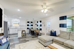 A modern living room with a sofa, a coffee table, and a dining area with a table and chairs.