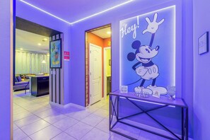 Relax in our welcoming lobby, featuring a vibrant space with a Mickey Mouse poster and a seating area with a sofa and table.