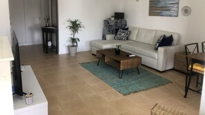 A living room with a sofa, coffee table, TV, and decorative items. - Refúgio Ls (Guia)