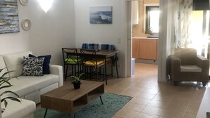 A living room with a sofa, coffee table, and a dining area with chairs and a table. - Refúgio Ls (Guia)