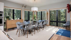 A modern dining area with a large table, chairs, and a hanging light fixture.