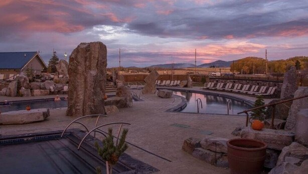 A resort pool area with multiple pools, large rocks, and lounge chairs.